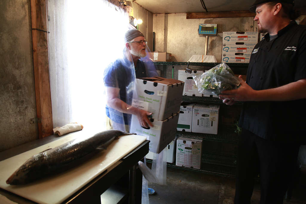 Men carrying boxes of produce in a refrigerated room