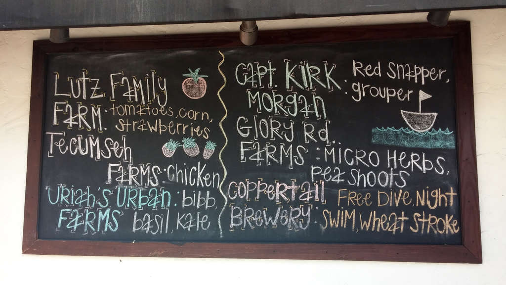 Another hand-drawn chalkboard sign listing several local farms and suppliers