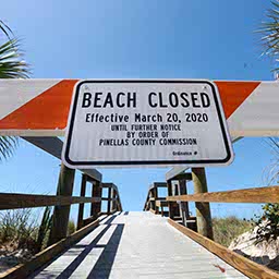 Beach entry boardwalk blocked by a barrier with a sign 